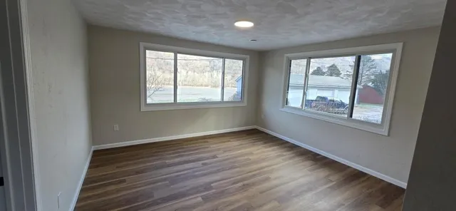 a view of an empty room with wooden floor and a window