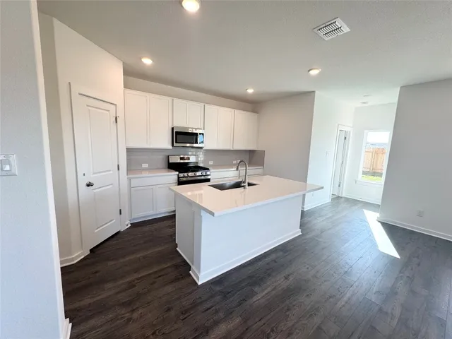 a large white kitchen with wooden floors and stainless steel appliances