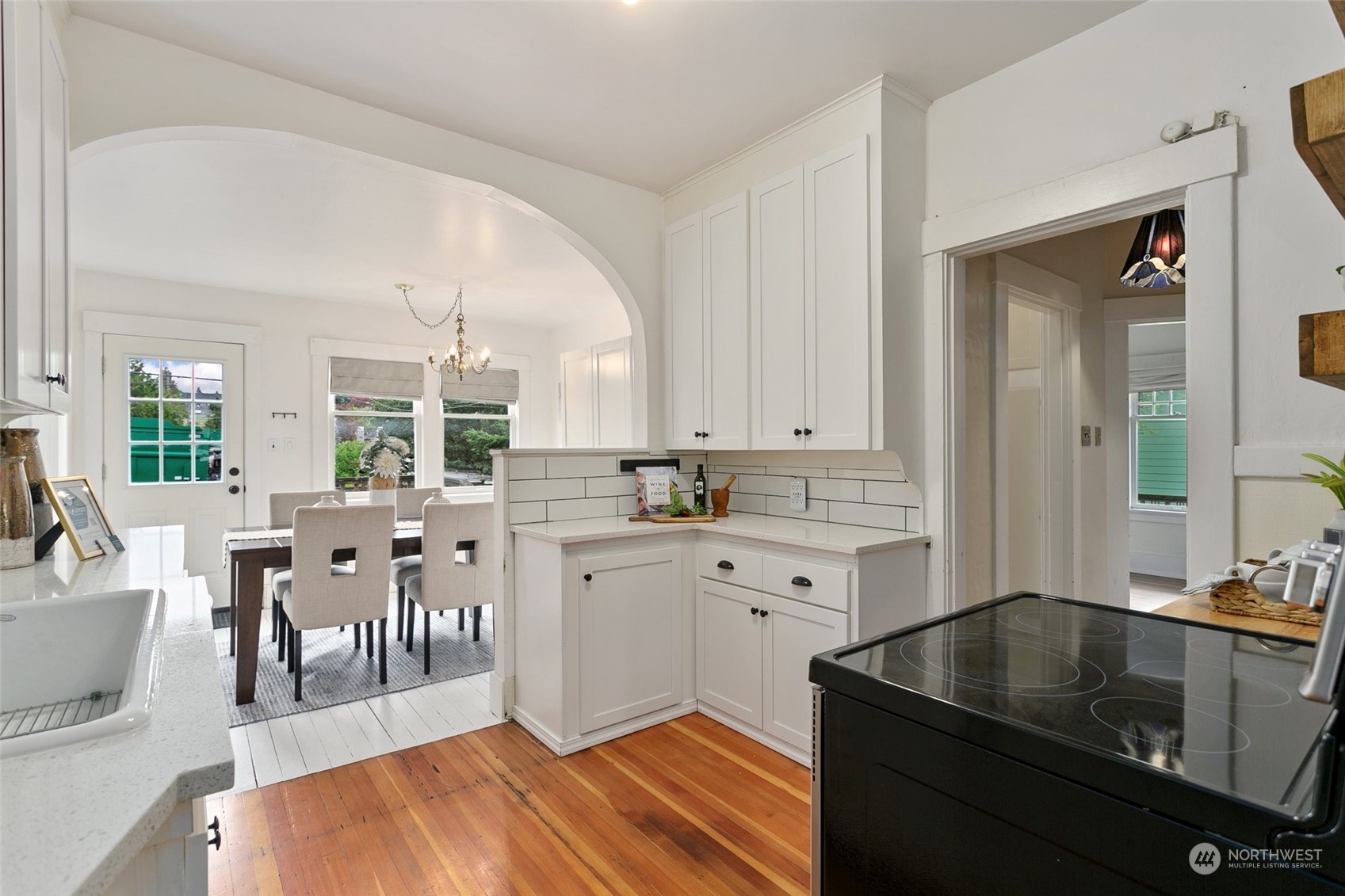 5942 41st Avenue Southwest Seattle, WA 98136 - Photo 16 of 40 a kitchen with stainless steel appliances granite countertop a sink dishwasher and white cabinets with wooden floor
