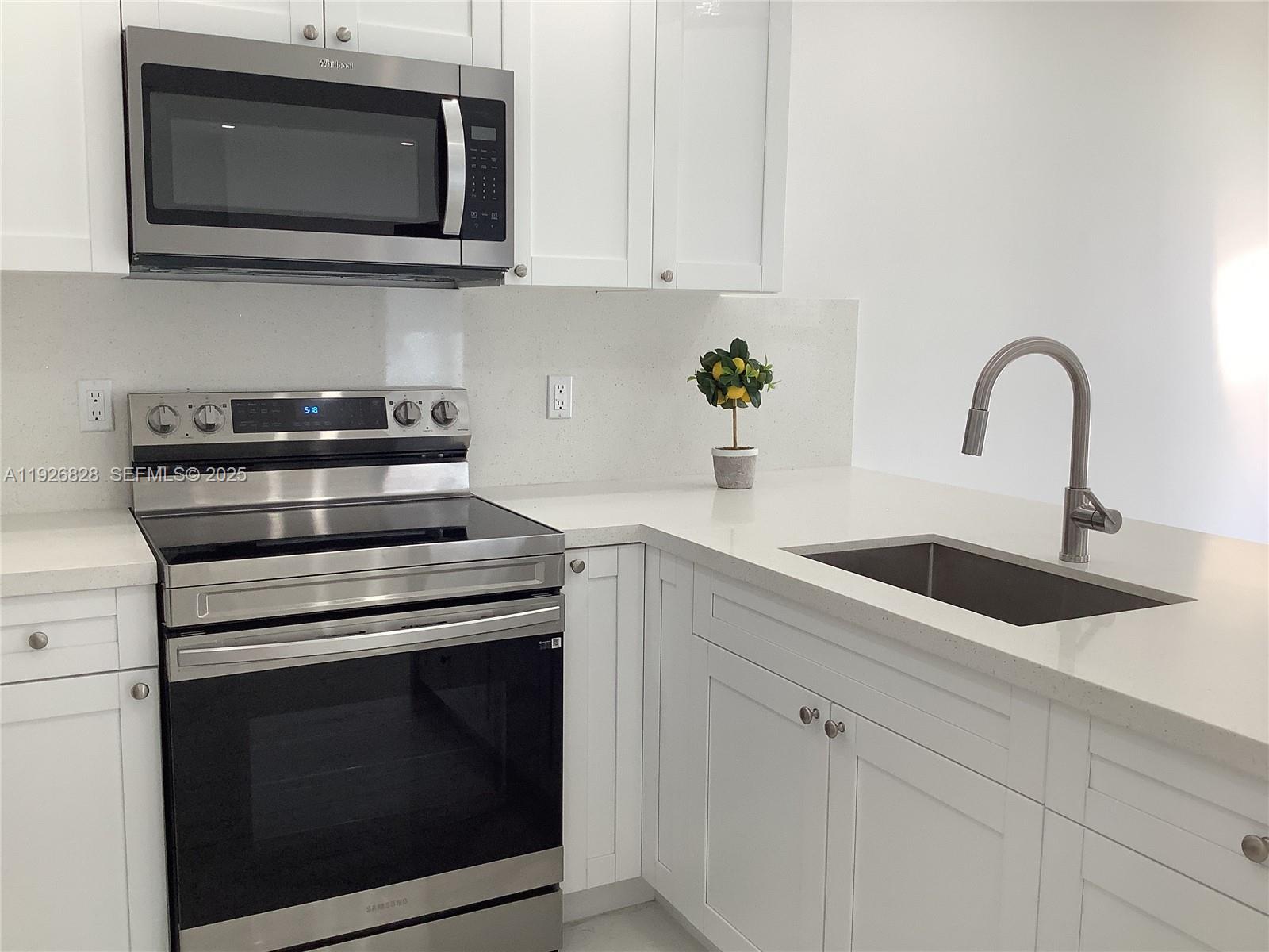 1653 Southwest 17th Terrace, Unit FRONT Miami, FL 33145 - Photo 16 of 25 a kitchen with stainless steel appliances granite countertop white cabinets a stove top oven and sink