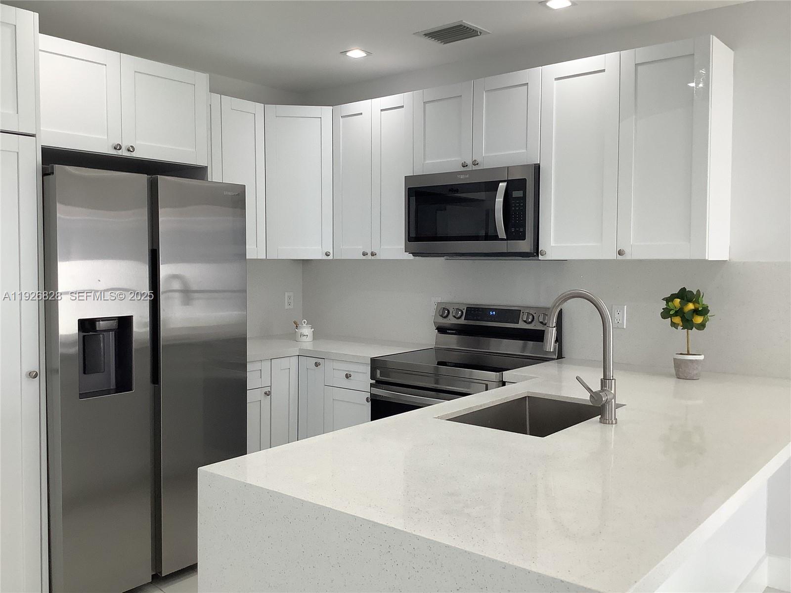 1653 Southwest 17th Terrace, Unit FRONT Miami, FL 33145 - Photo 19 of 25 a kitchen with stainless steel appliances granite countertop a refrigerator a sink a stove a microwave and white cabinets