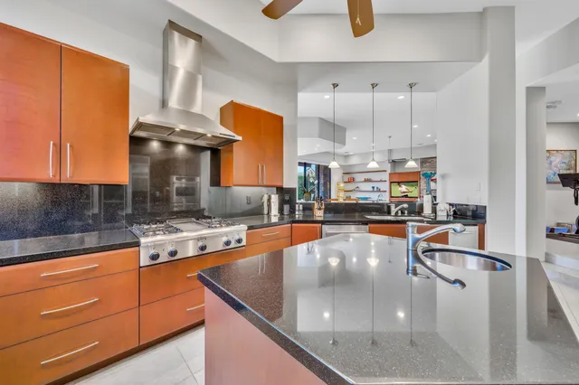 a kitchen with stainless steel appliances granite countertop a sink a stove and a refrigerator