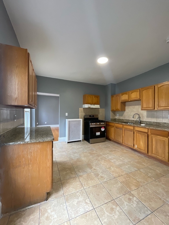 a large kitchen with stainless steel appliances granite countertop a sink and cabinets