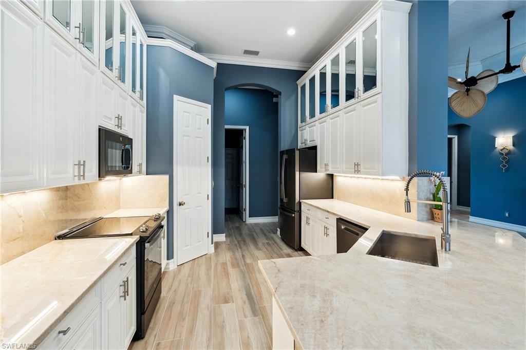 8239 Potomac Lane Naples, FL 34104 - Photo 11 of 47 a kitchen with stainless steel appliances kitchen island granite countertop a refrigerator and a stove top oven