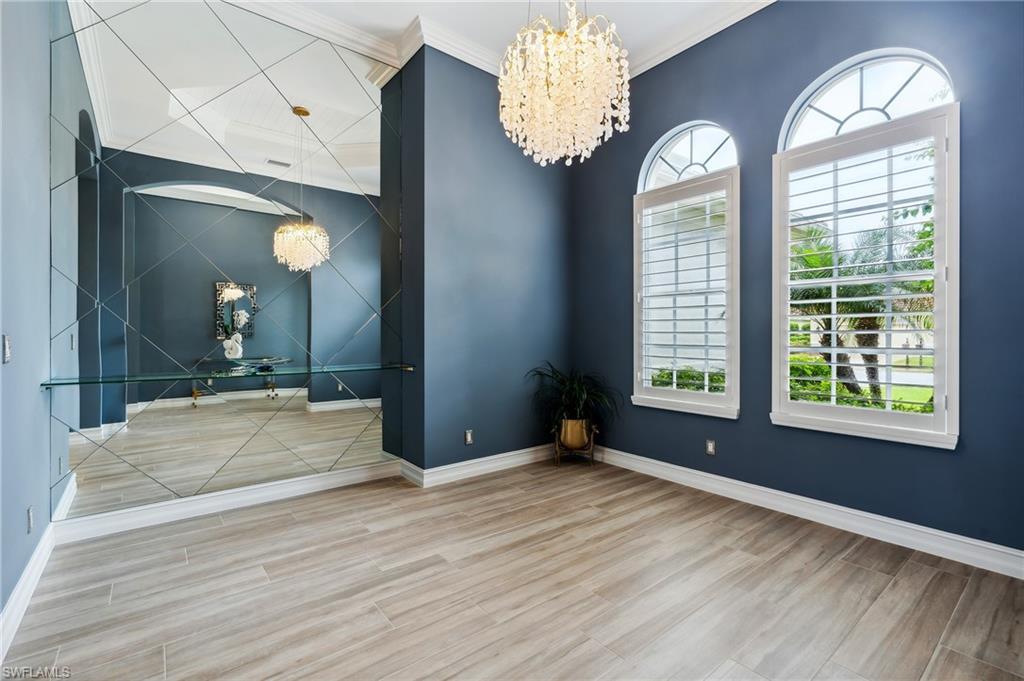 8239 Potomac Lane Naples, FL 34104 - Photo 21 of 47 a spacious bedroom with a large bed chandelier and a window