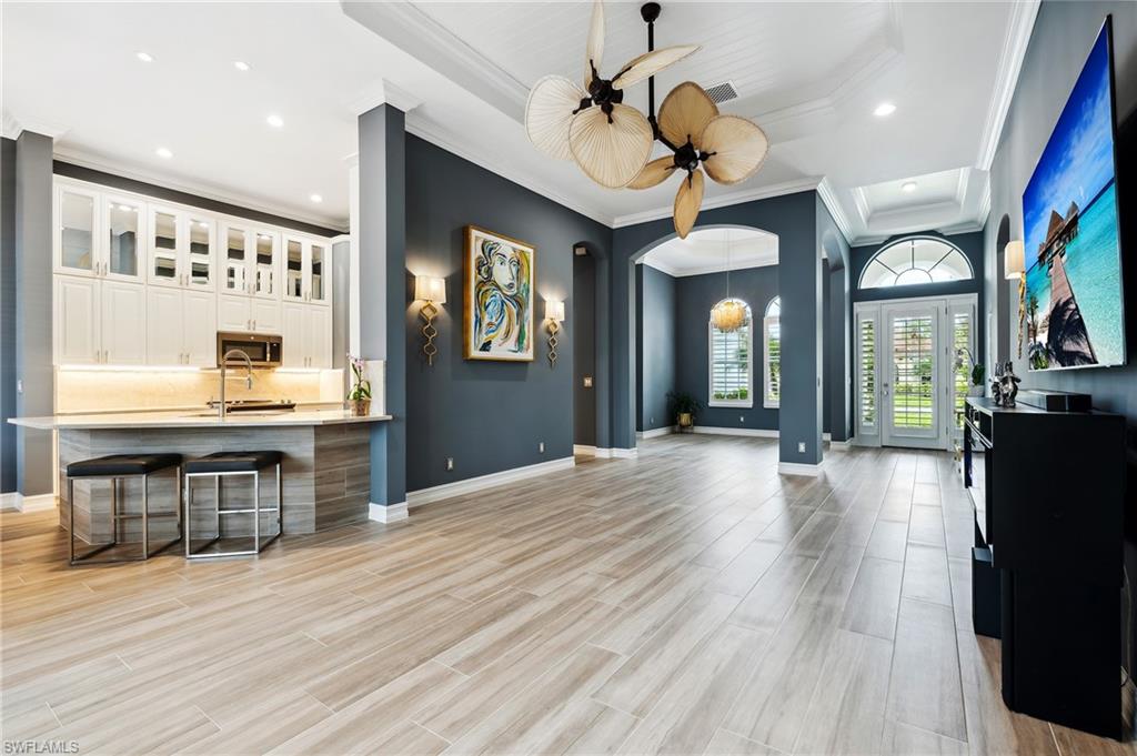 8239 Potomac Lane Naples, FL 34104 - Photo 26 of 47 a view of a room with wooden floor a ceiling fan window and a kitchen