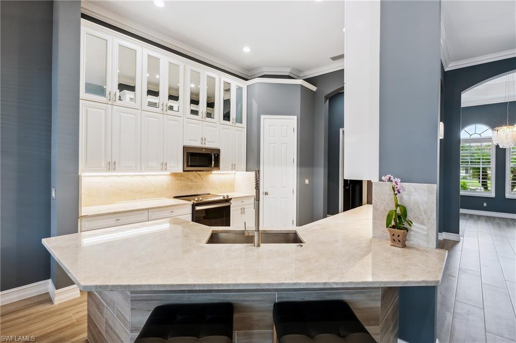 8239 Potomac Lane Naples, FL 34104 - Photo 10 of 47 a kitchen with stainless steel appliances granite countertop a table chairs and refrigerator
