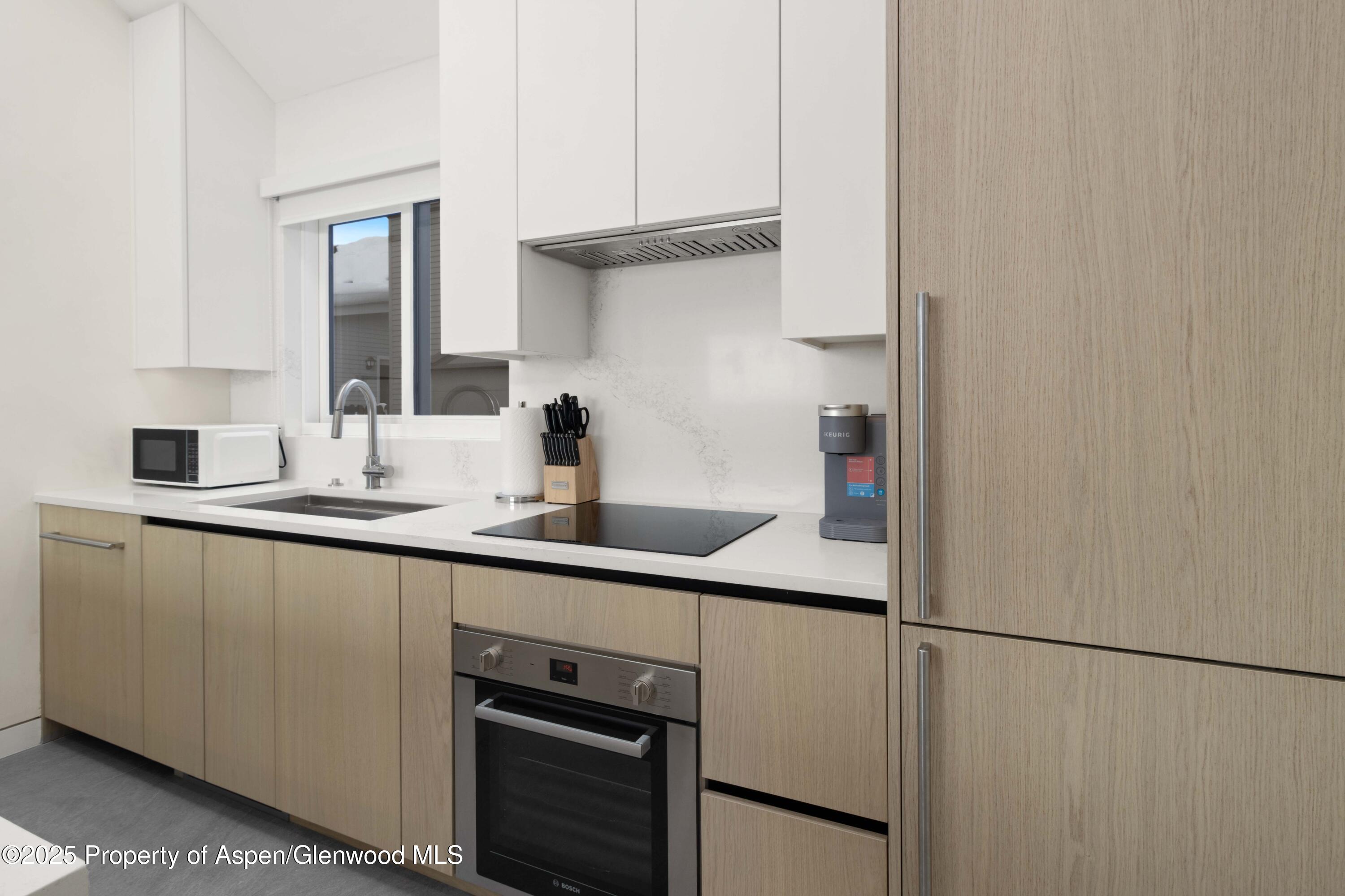 211 West Main Street, Unit 103 Aspen, CO 81611 - Photo 2 of 4 a kitchen with a sink and white cabinets