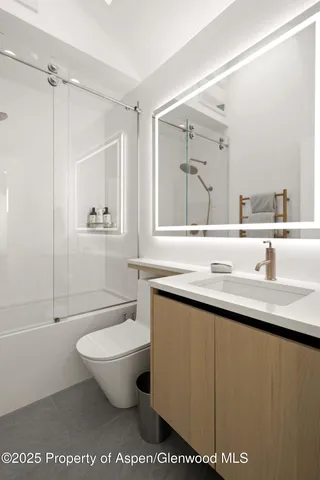 a bathroom with a granite countertop sink a toilet a mirror and shower