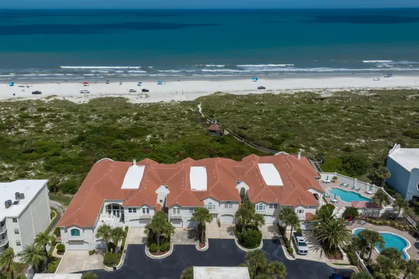 an aerial view of ocean and residential houses with outdoor space