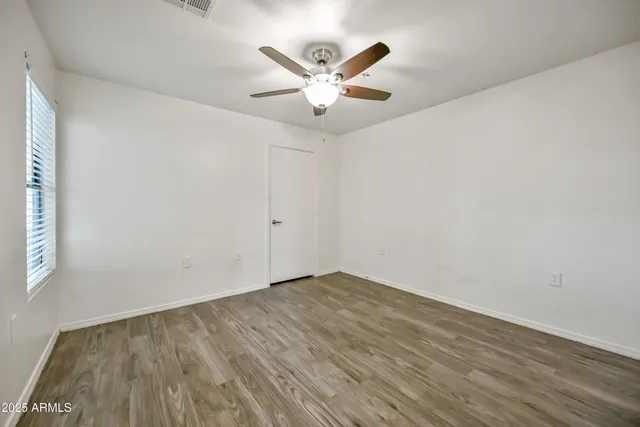 an empty room with wooden floor and ceiling fan