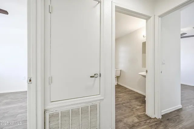 an empty room with wooden floor fan and windows