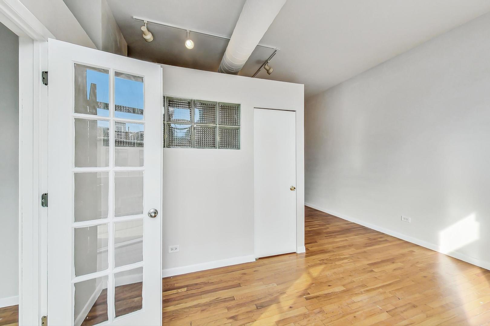 400 North Racine Avenue, Unit 217 Chicago, IL 60642 - Photo 7 of 29 an empty room with wooden floor and windows