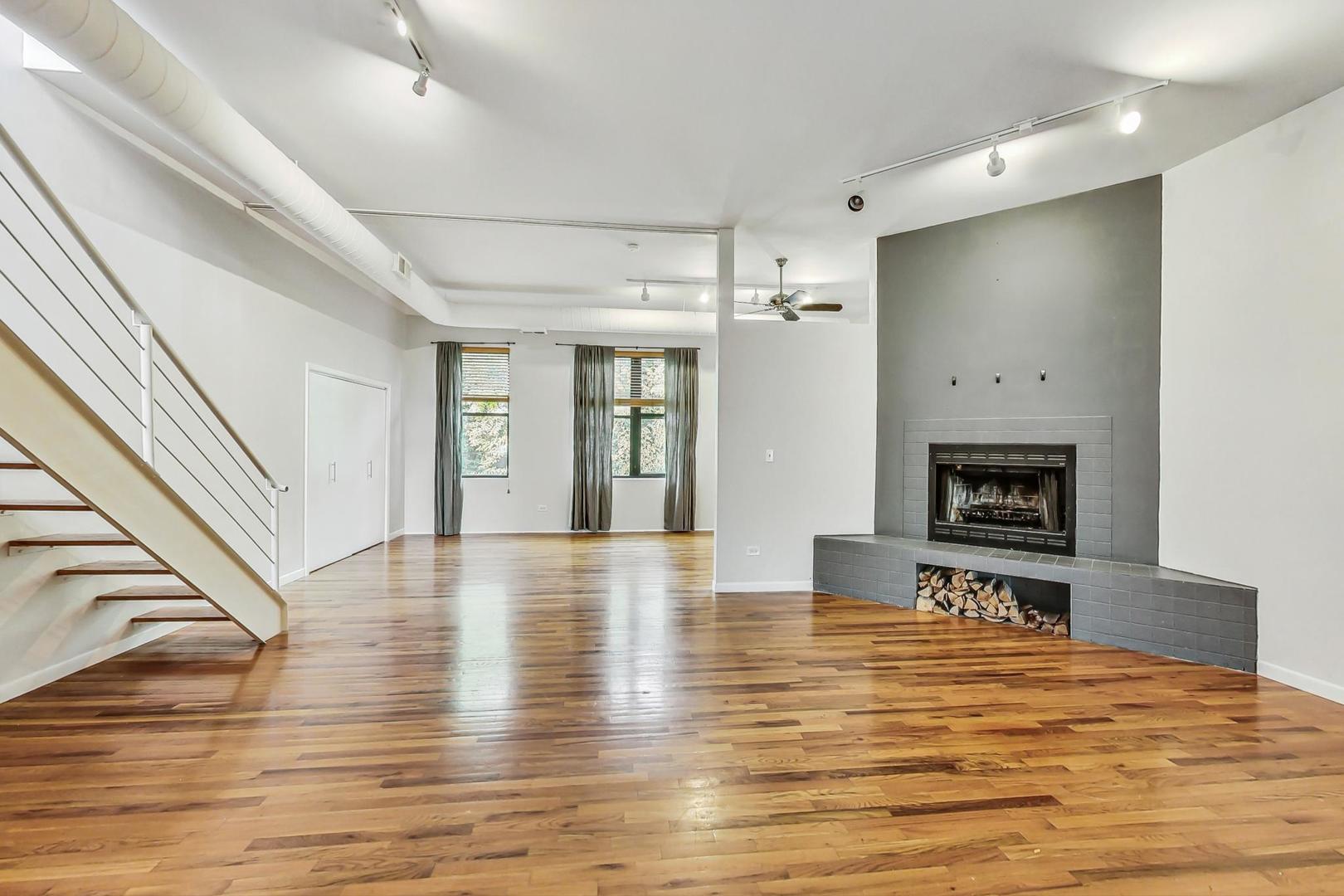 400 North Racine Avenue, Unit 217 Chicago, IL 60642 - Photo 10 of 29 a view of an empty room with wooden floor and a fireplace