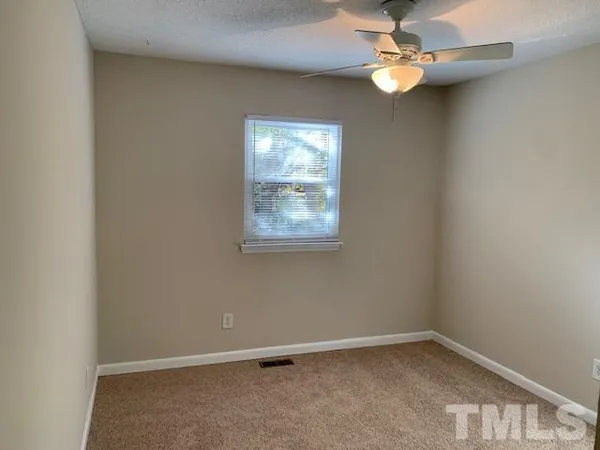 an empty room with windows and fan