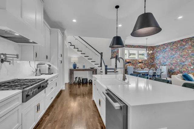 a kitchen with granite countertop a stove a sink a dining table and chairs