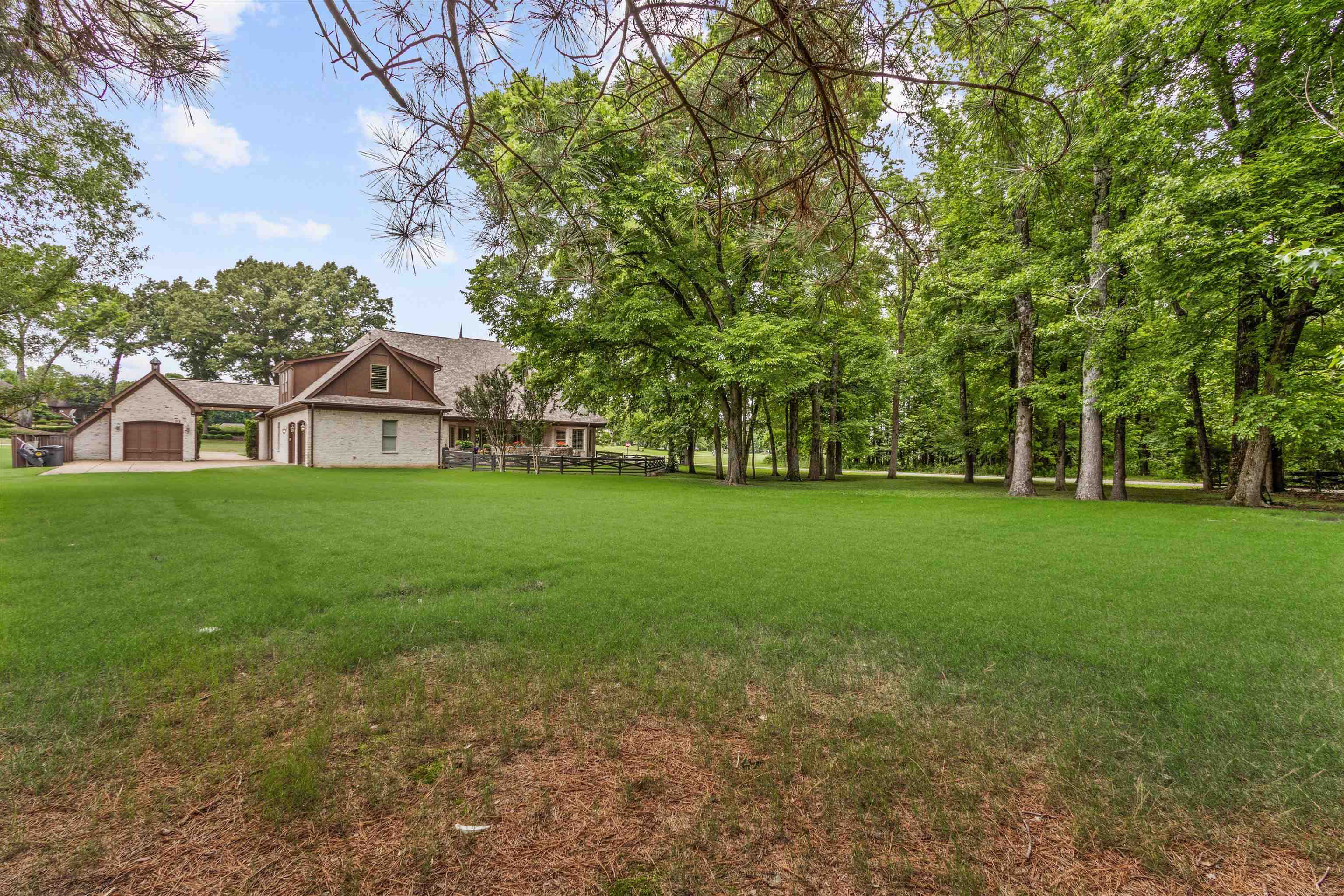 150 Ridgecrest Drive Arlington, TN 38002 - Photo 32 of 40 Expansive green lawn framed by mature trees, leading to a light brick residence with a prominent gabled roofline and multiple dormer windows