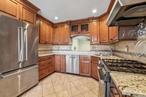 a kitchen with granite countertop a refrigerator stove top oven and sink