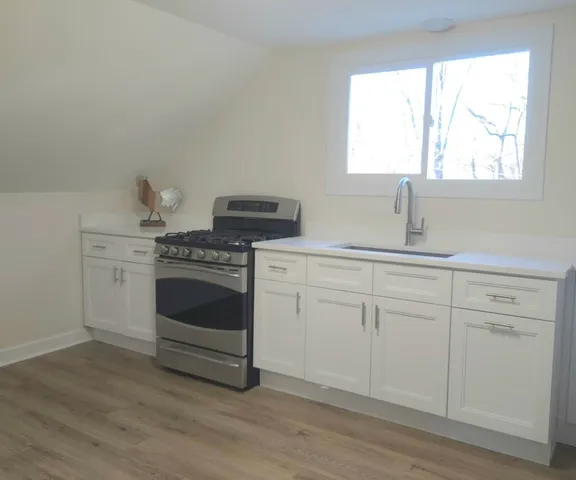 a kitchen with white cabinets appliances and a window
