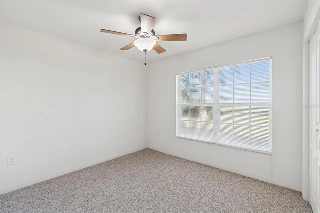 an empty room with a ceiling fan and a window