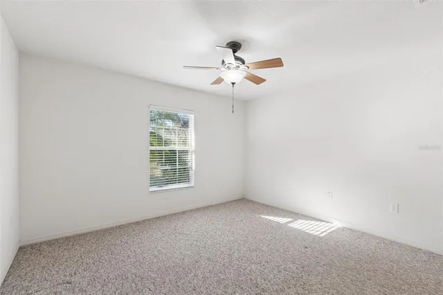 an empty room with a window and a fan