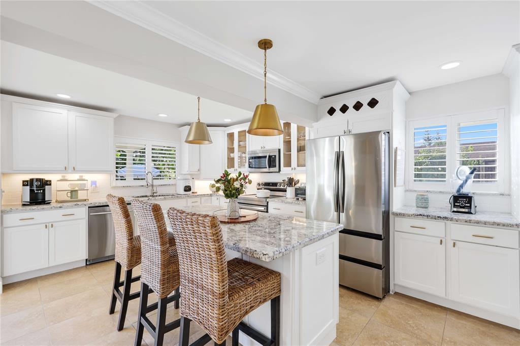 491 Northwest 13th Drive Boca Raton, FL 33486 - Photo 6 of 48 a kitchen with stainless steel appliances kitchen island granite countertop a kitchen island a stove a table and chairs