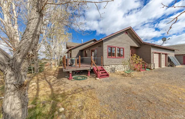 a view of house with outdoor seating and covered with trees