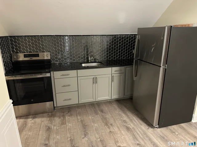 a kitchen with granite countertop a refrigerator and a sink