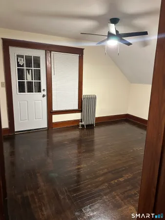 a view of empty room with wooden floor and fan