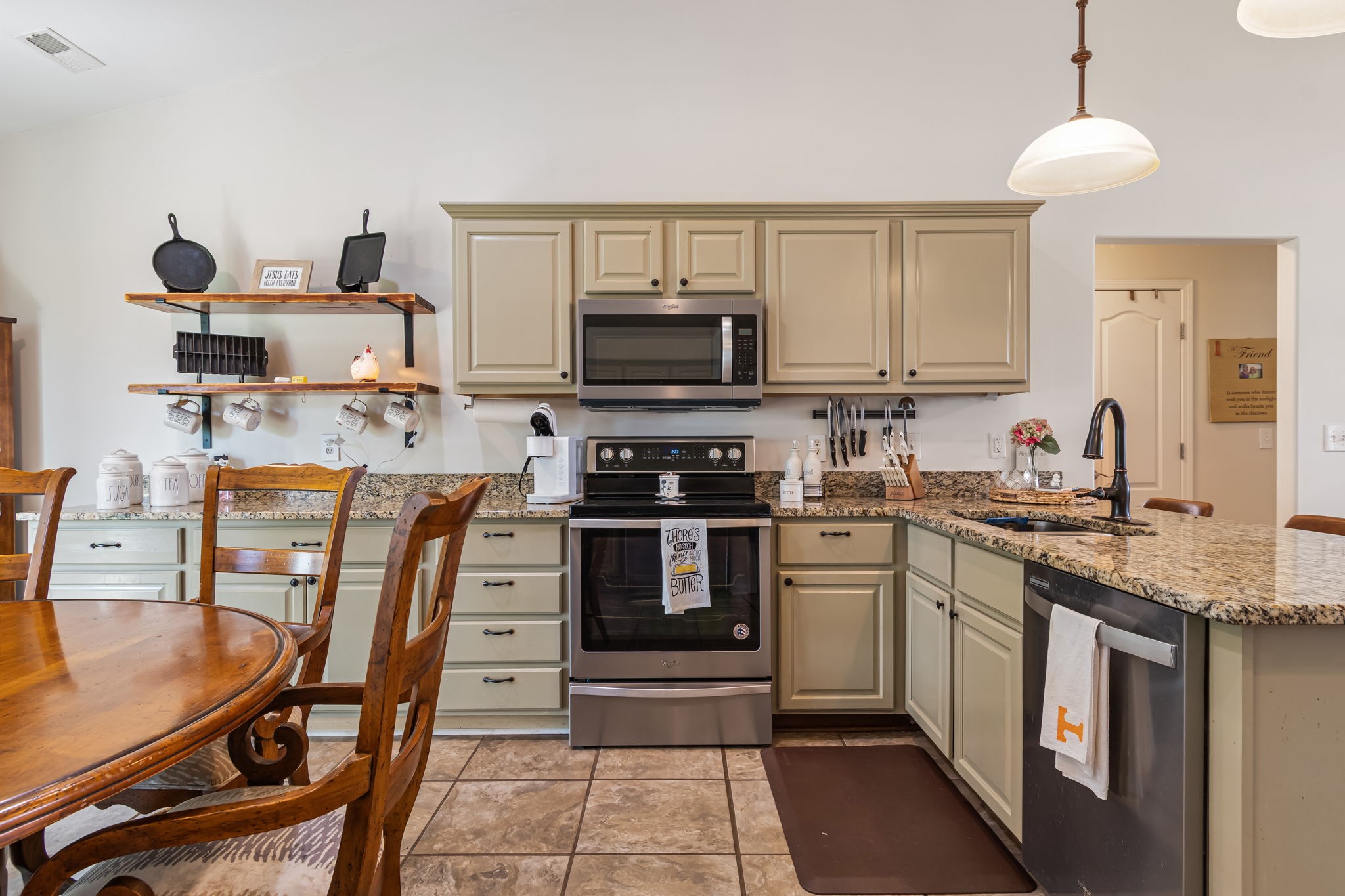 4989 Morning Dove Lane Spring Hill, TN 37174 - Photo 11 of 28 a kitchen with stainless steel appliances granite countertop a stove top oven a sink a dining table and chairs