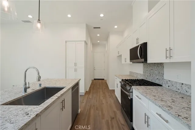 a kitchen with stainless steel appliances granite countertop a stove a sink and a wooden floors