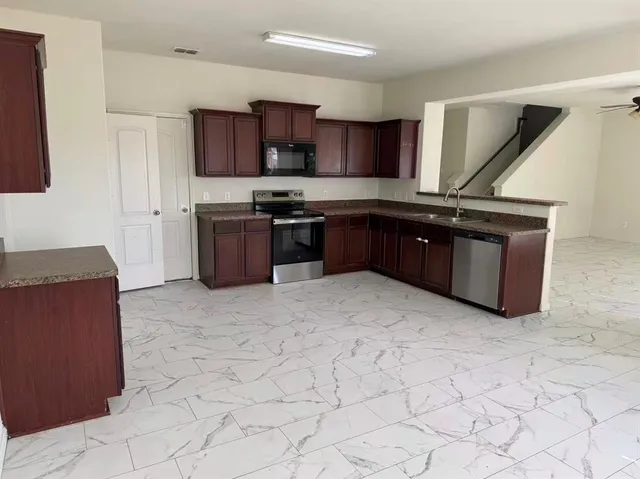 a kitchen with stainless steel appliances granite countertop a stove a sink a microwave and a refrigerator