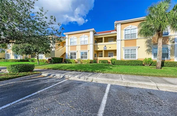 a view of a brick building next to a yard with large trees
