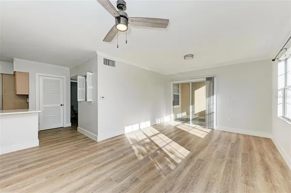 a view of empty room with wooden floor and fan