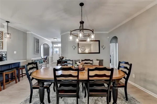 a view of a dining room and livingroom with furniture wooden floor a rug a painting and a chandelier