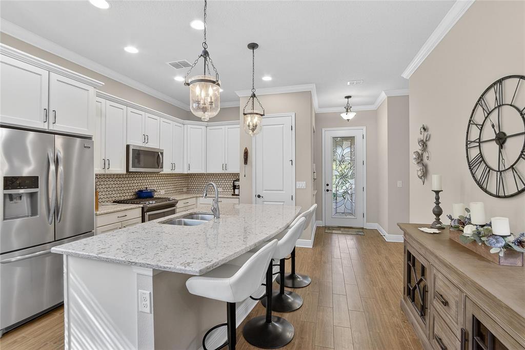 6020 Plover Meadow Street Lithia, FL 33547 - Photo 9 of 41 a kitchen with granite countertop a table chairs stainless steel appliances and cabinets