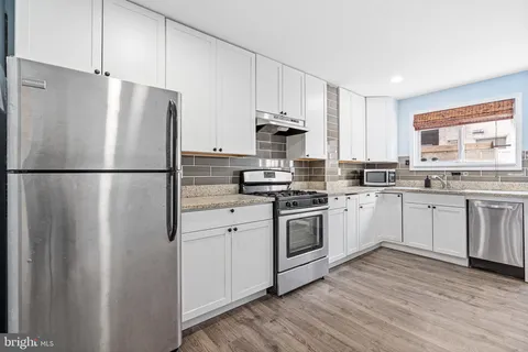 a kitchen with stainless steel appliances a refrigerator sink and white cabinets