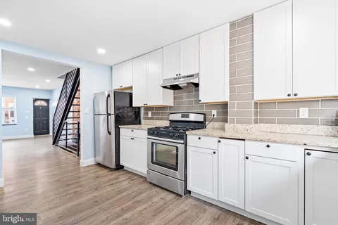 a kitchen with a sink stainless steel appliances and wooden floor