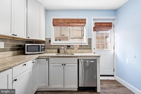 a kitchen with stainless steel appliances granite countertop a sink and cabinets with wooden floor