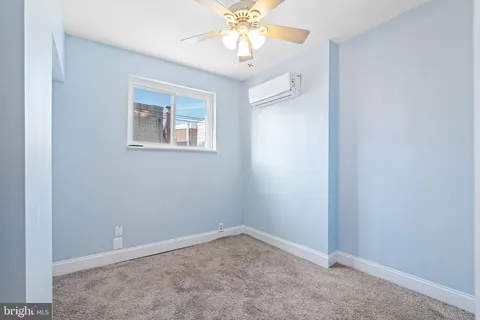 an empty room with a window and a chandelier fan