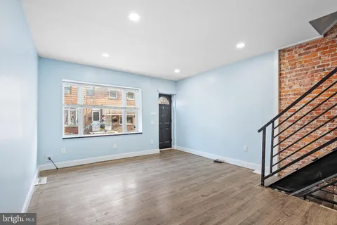 an empty room with wooden floor and window