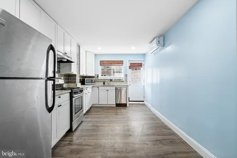a kitchen with white cabinets stainless steel appliances and a refrigerator