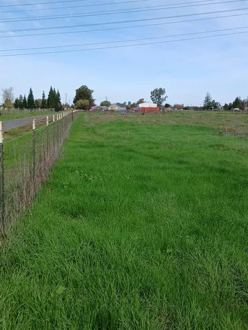 a yard with lots of green space and trees in the background
