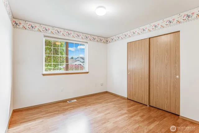 an empty room with wooden floor fan and windows