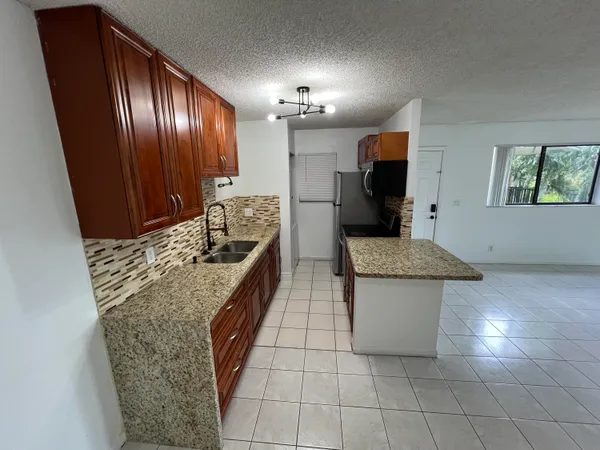 a kitchen with granite countertop a stove a sink and a refrigerator