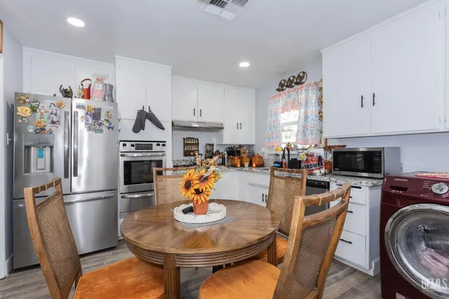 a kitchen with stainless steel appliances kitchen island granite countertop a dining table and chairs