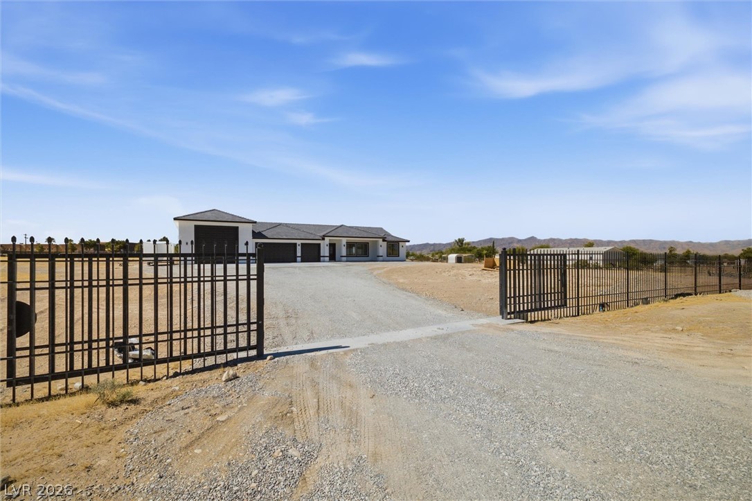 5910 East Kellogg Road Pahrump, NV 89061 - Photo 1 of 58 Securely gated estate, featuring a spacious home with multiple garage bays, nestled amidst a wide-open landscape.