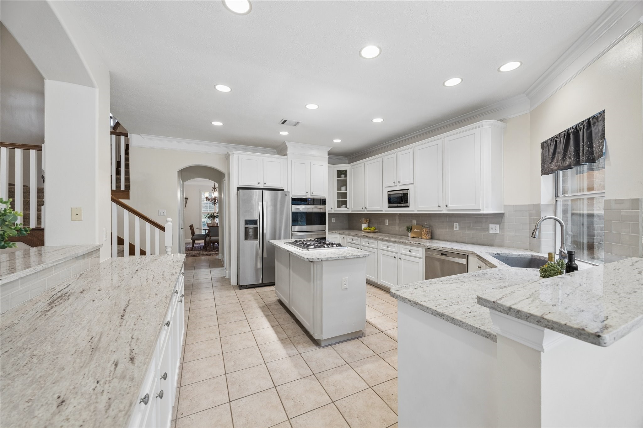14530 Millhouse Road Pinehurst, TX 77362 - Photo 15 of 46 View from the breakfast area highlighting the kitchen’s U-shaped layout, extended counter space, recessed lighting, stainless steel appliances and connectivity to the main living areas.