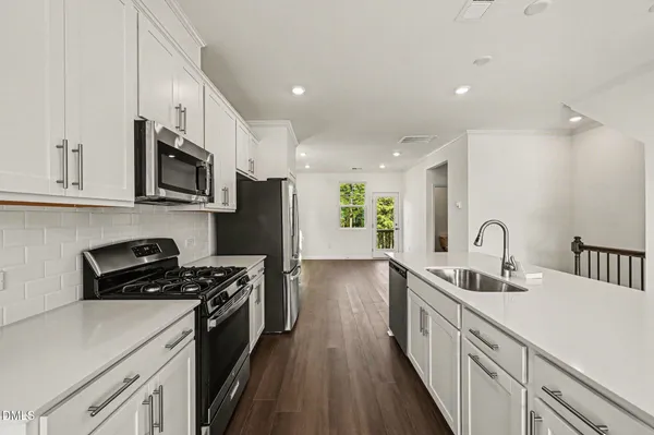 a kitchen with stainless steel appliances a sink a stove a microwave a refrigerator a sink and cabinets