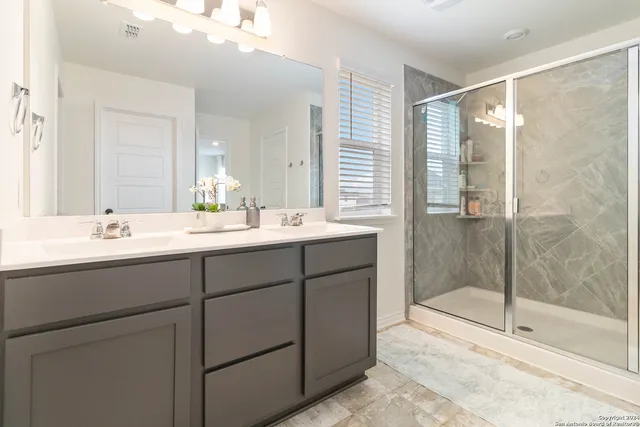 a bathroom with a double vanity sink mirror and shower
